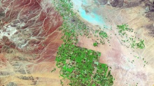 Satellite image of brown desert with patches of green