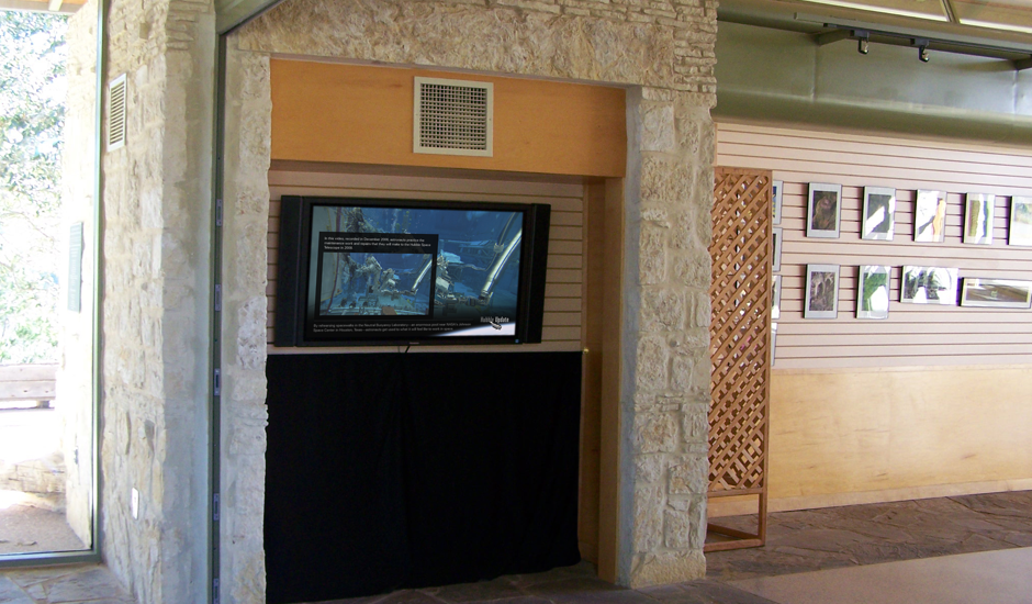 Photograph of a monitor showing a ViewSpace video. The monitor appears to be on a wall in a lobby area which also includes nature photos.