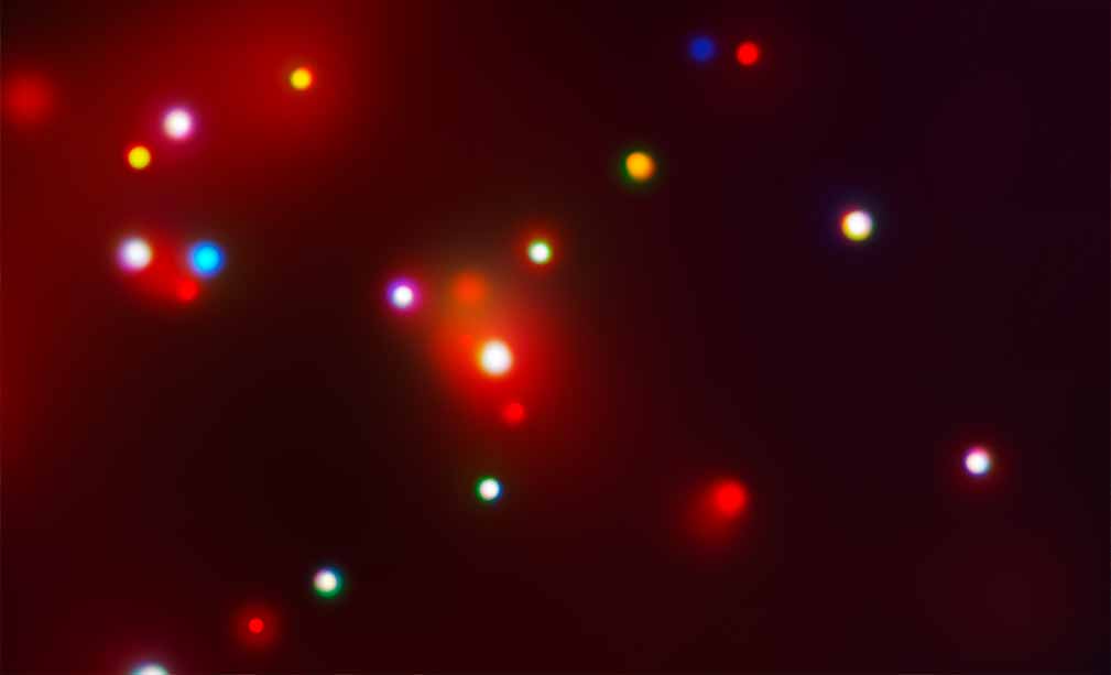 Color image of several wavelength-bands of X-ray light from the spiral galaxy M74 (the Phantom Galaxy). Although the perspective and field of view are the same as in the other images, this image is very different from the visible, mid-infrared, and ultraviolet images in terms of color, visible structure, and detail. Scattered across the image are glowing circles of various colors: bright red, bright blue, yellowish-orange, and white. The circles vary in size, but are typically much larger than the point-like stars in the visible and infrared images. They are somewhat fuzzy, but have more distinct outlines than the blue-white clumps in the ultraviolet image. The largest of these objects is located in the center of the image and appears to mark the core of the galaxy. It is bright white and is surrounded by a bright but diffuse red glow. This glow is present around some of the other objects and across the upper left portion of the image. Unlike in the visible, mid-infrared, and ultraviolet images, the spiral arms of the galaxy are not apparent in this image.