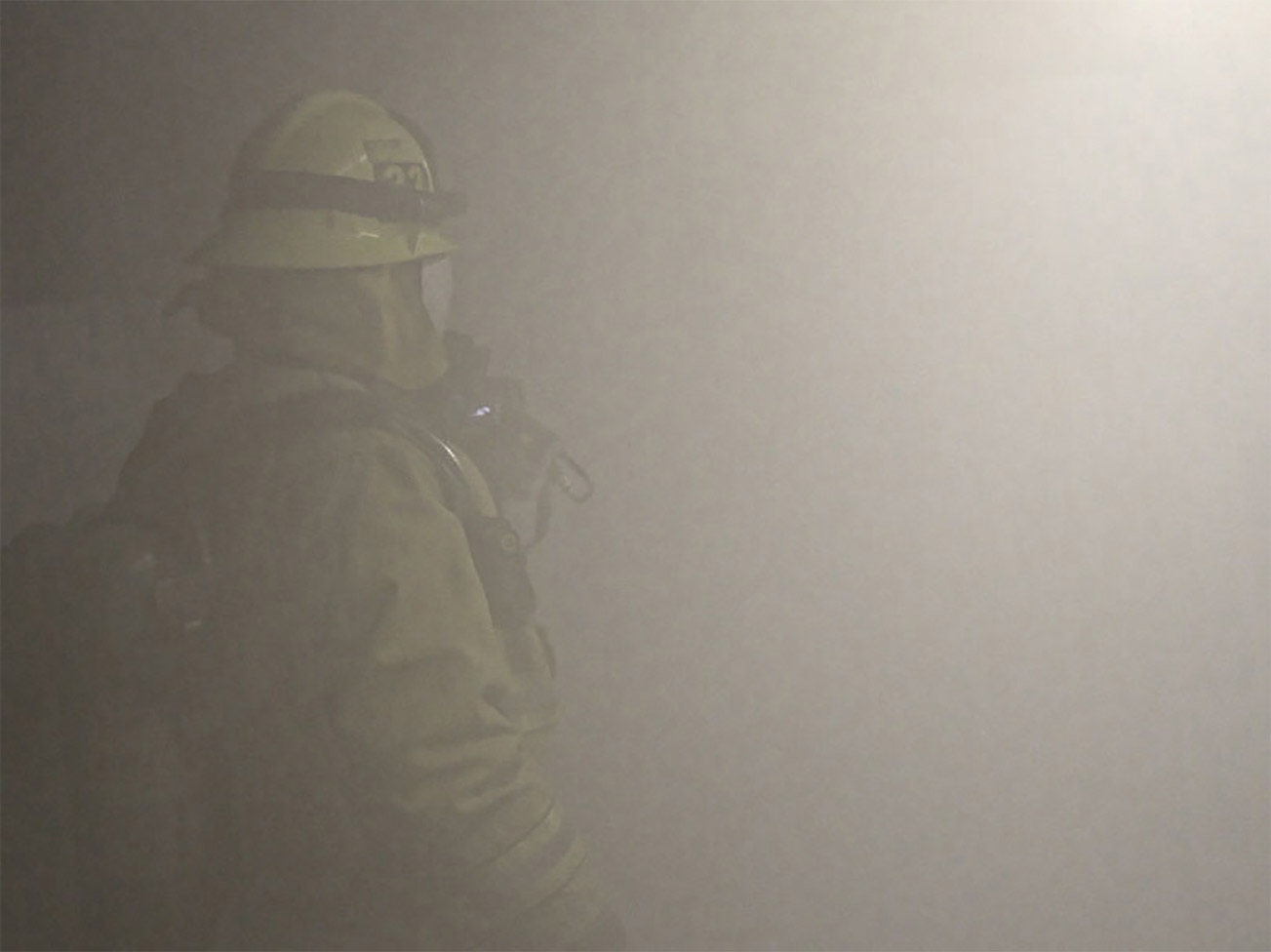 A firefighter stands in smoke