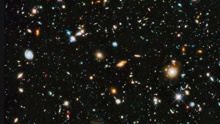 A field of galaxies: ovals and circles of different sizes, shapes, and colors set against the black background of space.