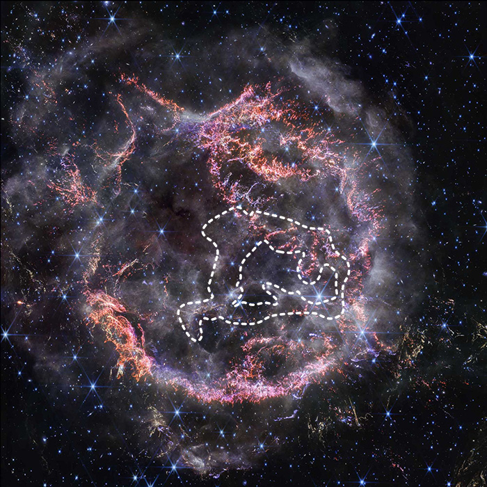 Cassiopeia A, a circular-shaped cloud of gas and dust with complex structure. The inner shell is made of bright pink and orange filaments studded with clumps and knots that look like tiny pieces of shattered glass. Around the exterior of the inner shell, particularly at the upper right, there are curtains of wispy gas that look like campfire smoke. The white smoke-like material also appears to fill the cavity of the inner shell, featuring structures shaped like large bubbles. Around and within the nebula, there are various stars seen as points of blue and white light.