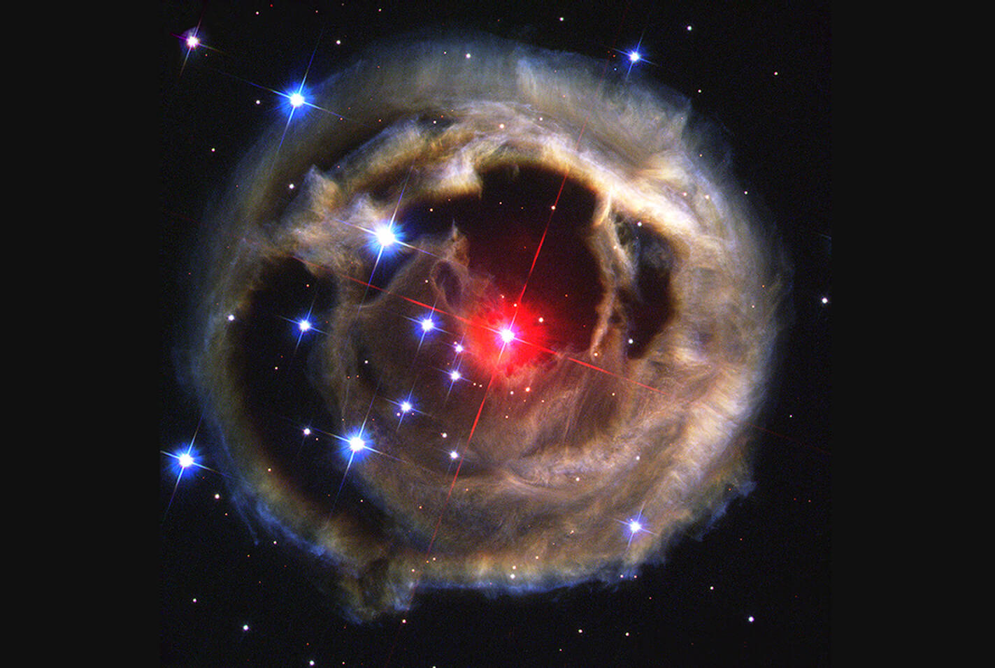 Star surrounded by dust varying from red to blue with holes
