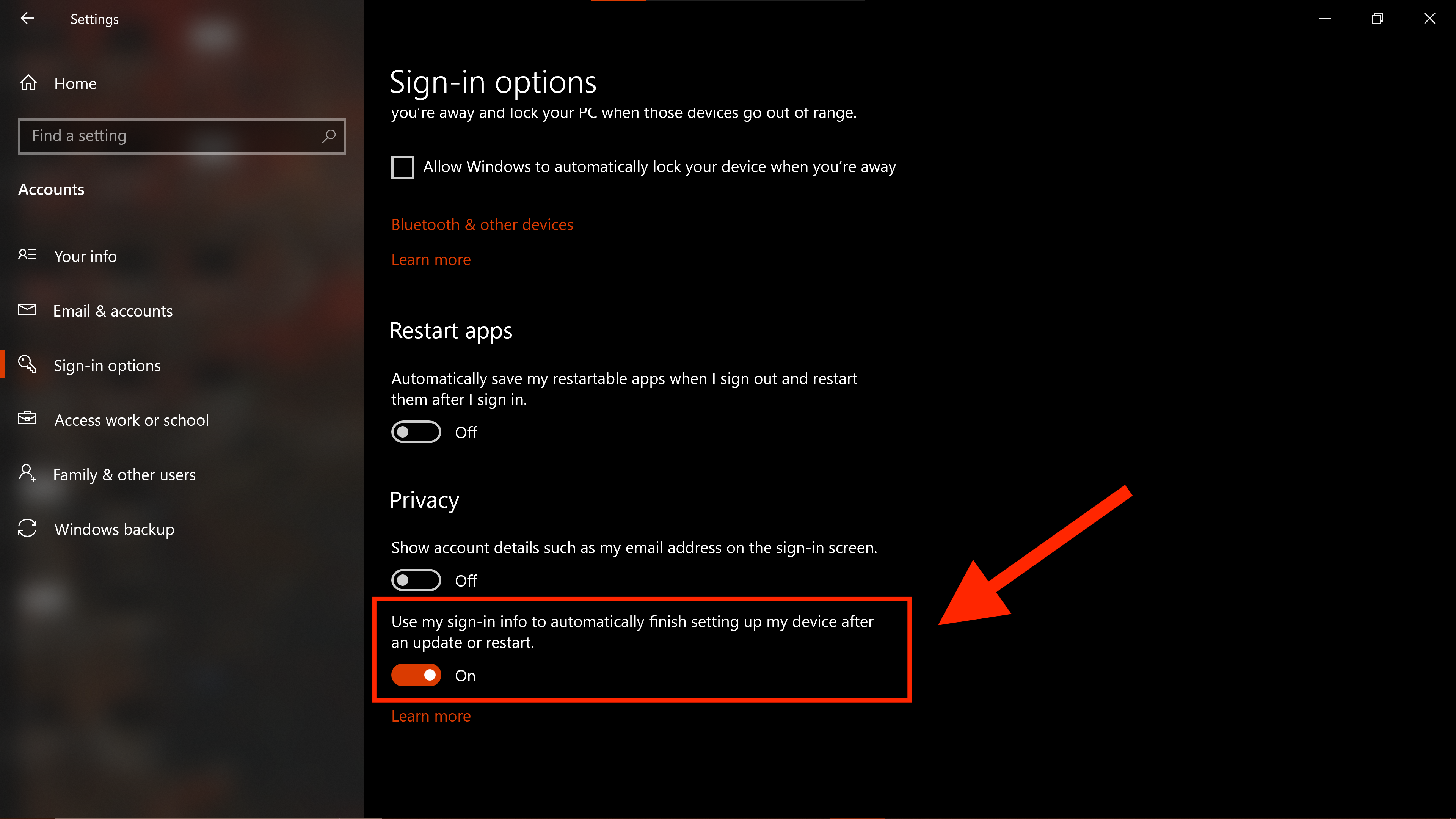 Screenshot of the Windows “Sign-in options” window. Toward the bottom, underneath the “Privacy” section, there are two buttons. The first "Show account details such as my email address on the sign-in screen" button is toggled "off." The second "Use my sign-in info to automatically finish setting up my device after an update or restart" is toggled "on" and has a large red arrow pointing toward it and a red rectangle surrounding it.