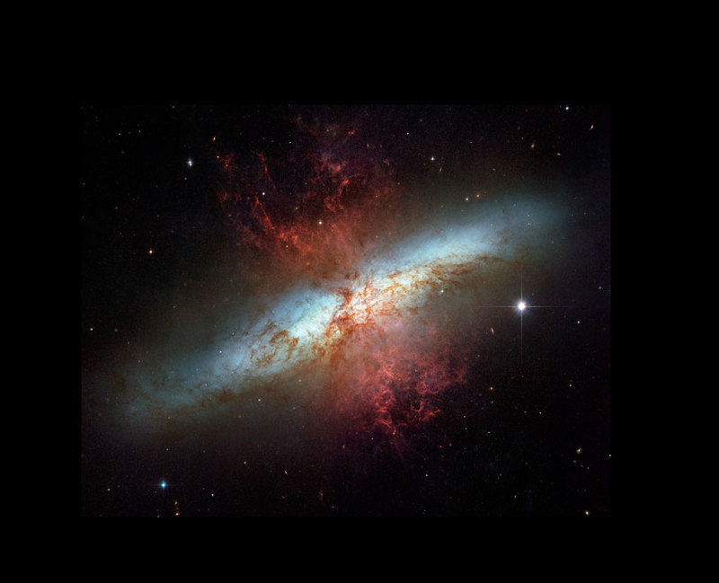 As each slider bar is manipulated, the view transitions from visible light to infrared light. In visible light: In visible light the edge-on disk highlights the geysers of hot gas shooting out of M82's core. In infrared light: Infrared light lets us see this galaxy's full disk of stars and reveals volumes of dust (shown in red) carried along with the hot gas.