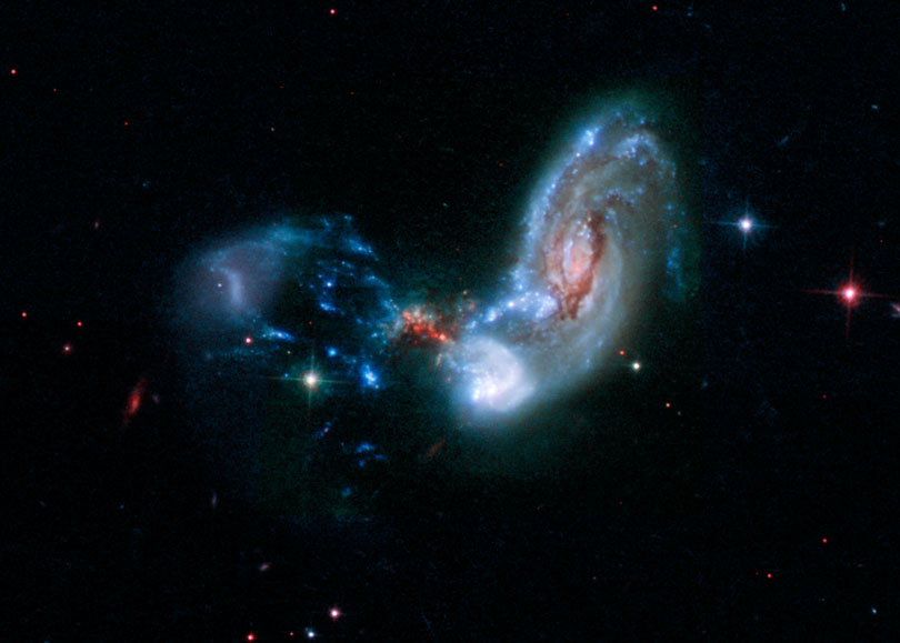 As each slider bar is manipulated, the view transitions from visible light to infrared light. In visible light: The merging galaxies are furiously forming stars inside a dark cocoon of dust. In infrared light: Including infrared light (in red) dramatically reveals where stars are forming.