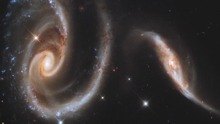 Two galaxies. The left galaxy is larger than the right.