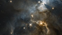 Image of the Bat Shadow: A dark scene with fluffy gray, blue, and brown gas and dust spread across it. A few bright stars appear toward bottom right.